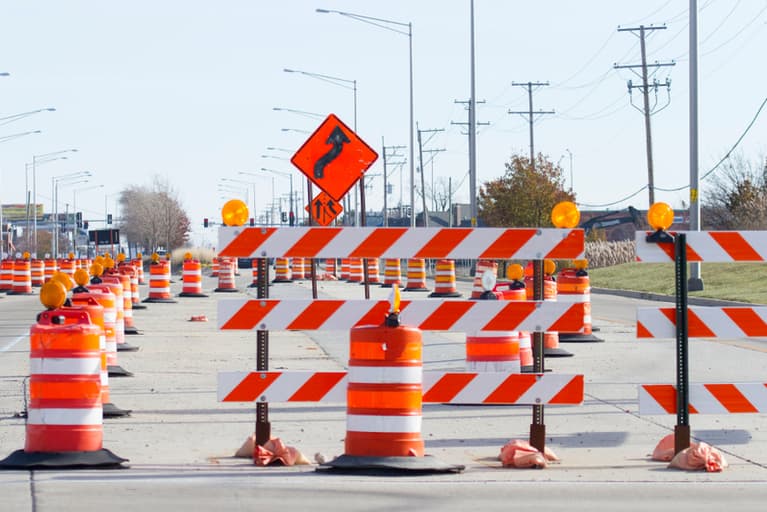 Type III barricades and drums lining a road work zone