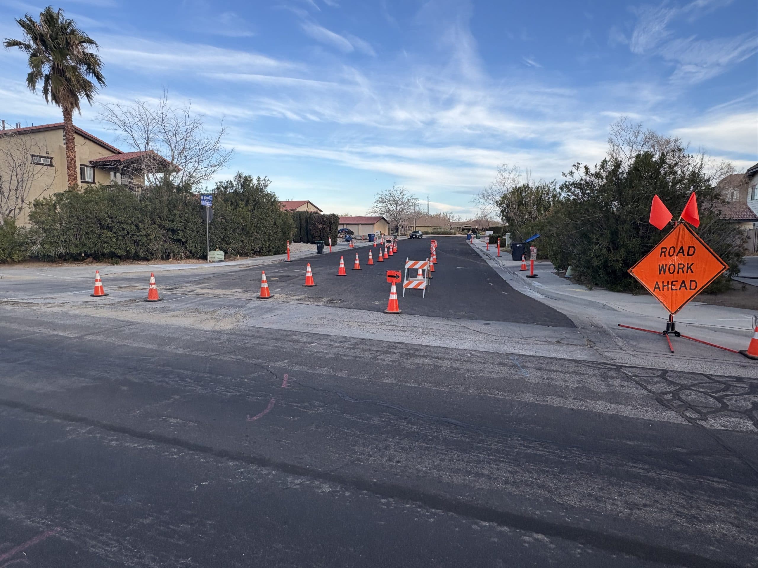 Road Work Ahead sign on a stand with a line of cones closing a lane